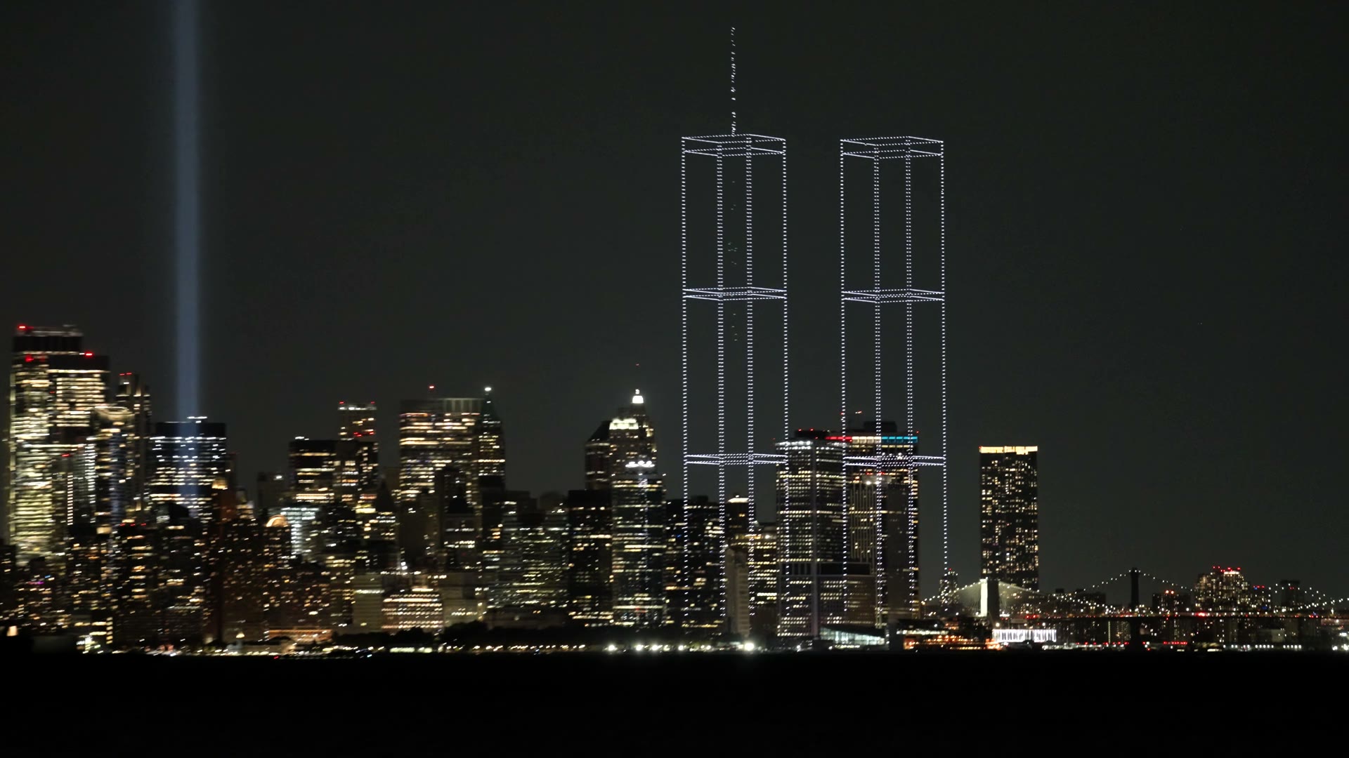 Film of two towers of light standing over the Lower Manhattan skyline at night